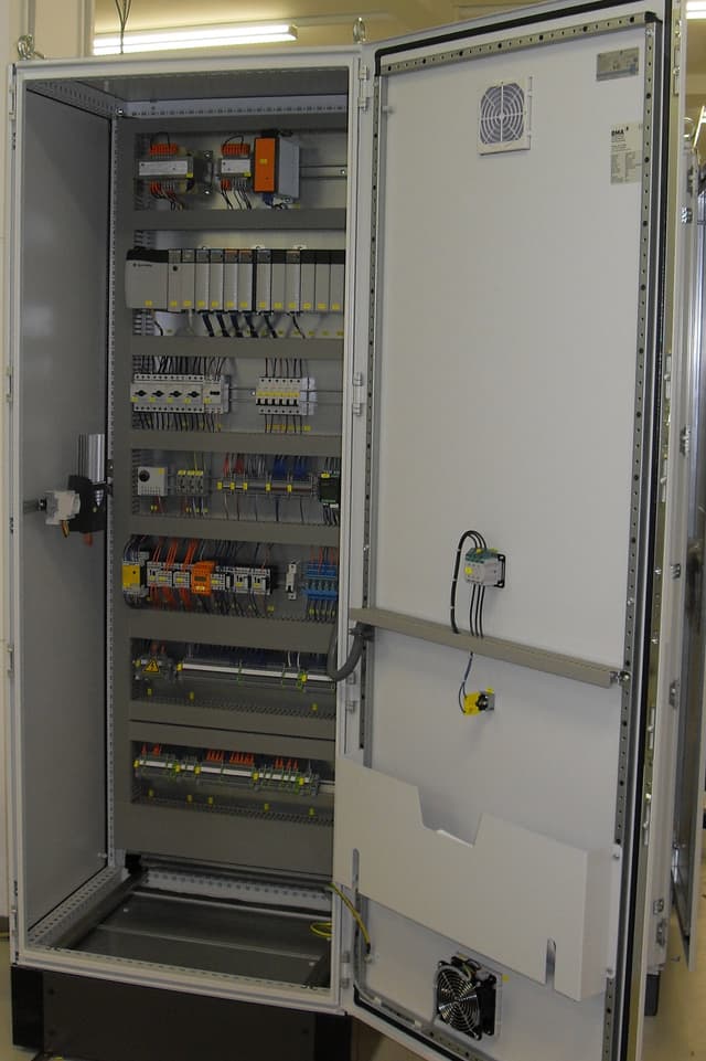 Inside of a UL 508A industrial control panel showing clean wire routing, labeled terminals, and DIN-rail mounted components